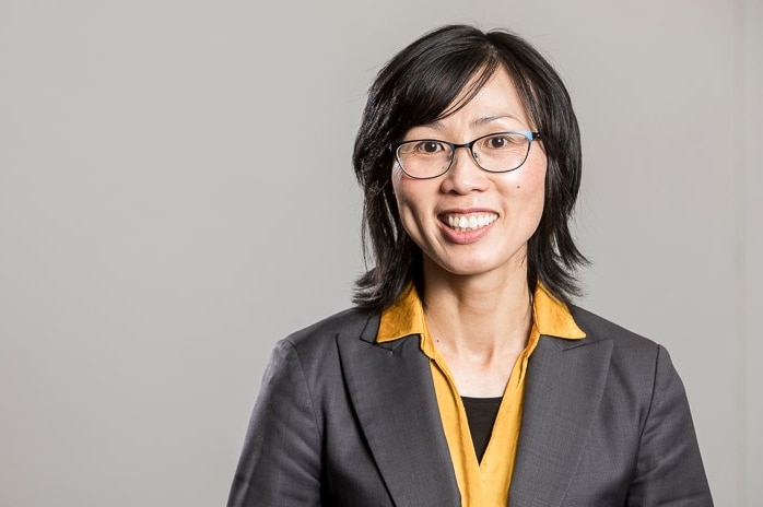 Vivienne Nguyen smiles while wearing a yellow shirt and grey blazer.