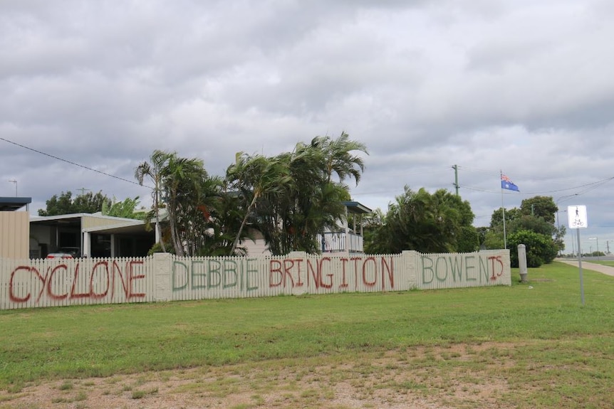 A fence reads: "Cyclone Debbie Bring it on"