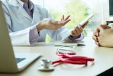 A doctor looks at an iPad while talking to patient.