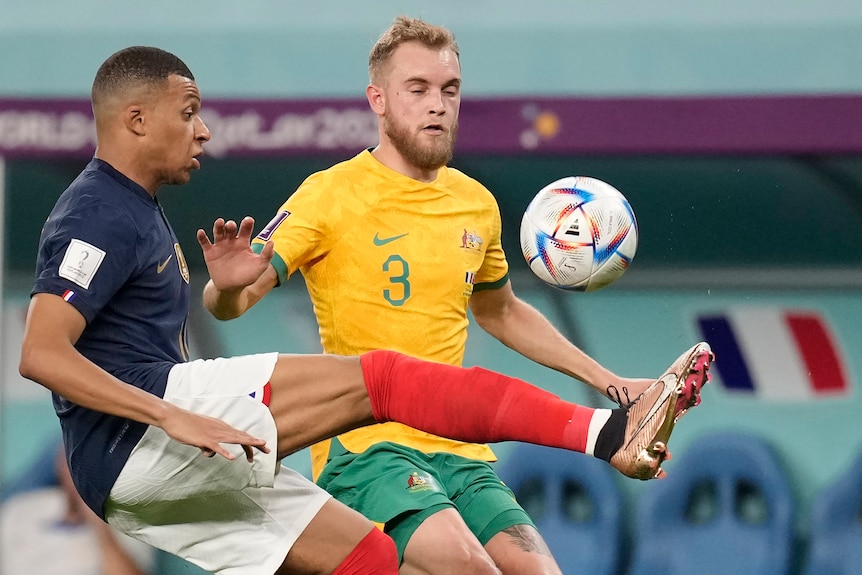 Kylian Mbappe of France kicks the ball as Australian Socceroos player Nathaniel Atkinson tries to defend at the Qatar World Cup.