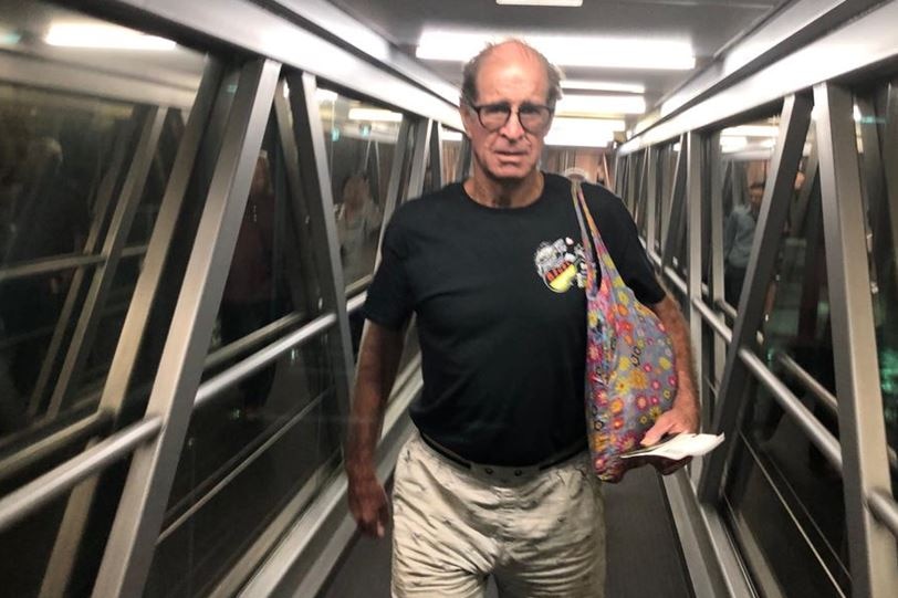 James Ricketson walks with boarding pass and passport in hand.