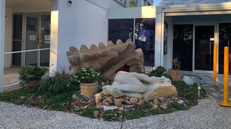 A sculpture of a female lying down, outside an art gallery