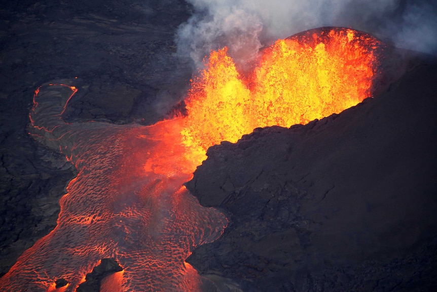 Lava erupts from a crater and flows away.