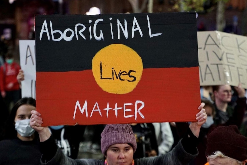 A protester holds up an Aboriginal Lives Matter placard in Sydney's CBD.