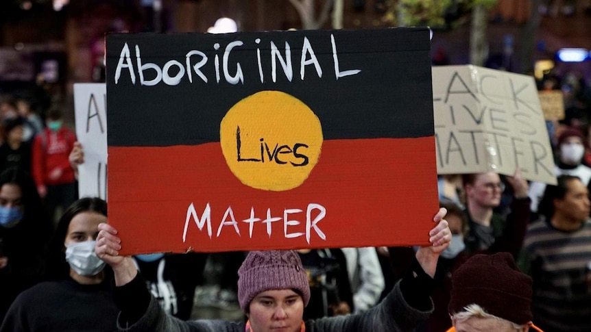 A protester holds up an Aboriginal Lives Matter placard in Sydney's CBD.