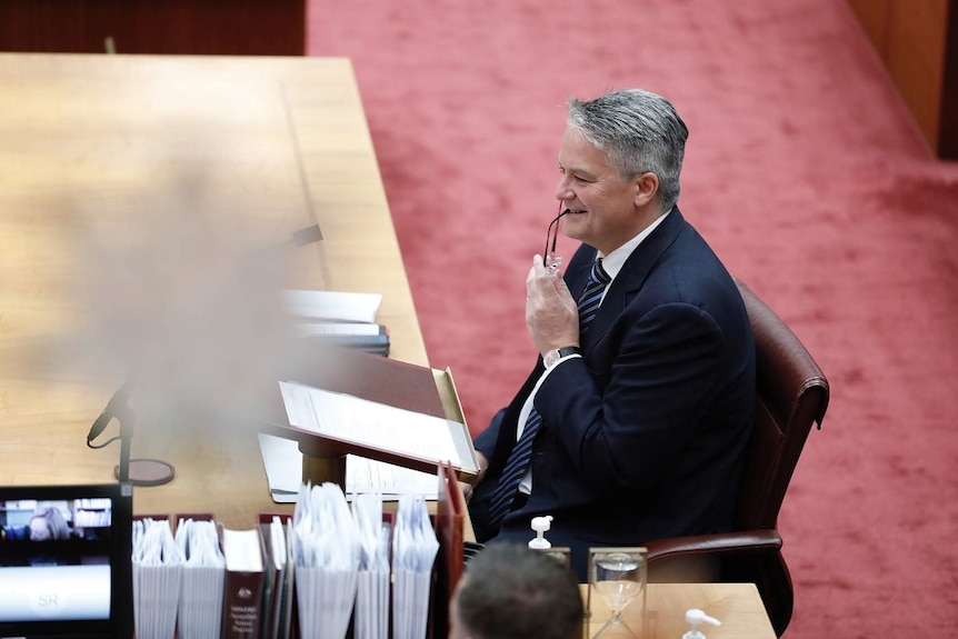 Mathias Cormann chews his glasses in the Senate.