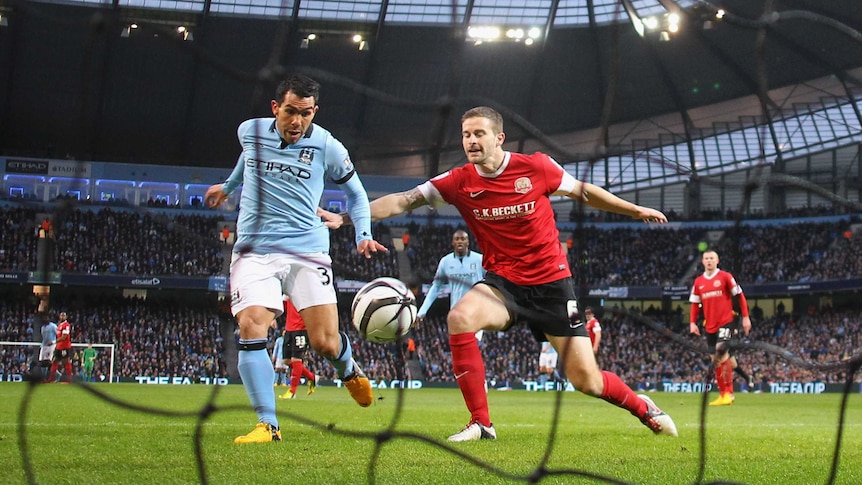 On target ... Carlos Tevez (L) beats Stephen Foster to score the opening goal