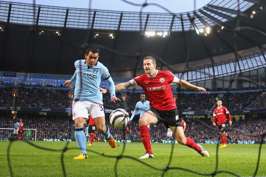 On target ... Carlos Tevez (L) beats Stephen Foster to score the opening goal