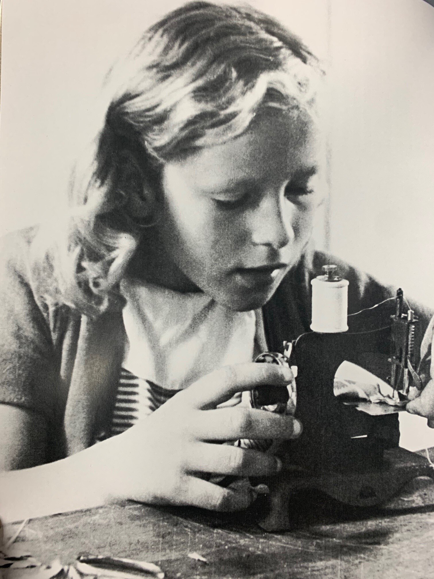 young girl operating a small sewing machine 