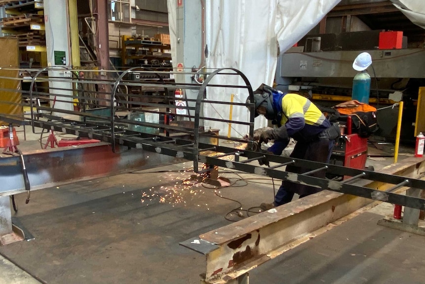 A worker welding a metal frame