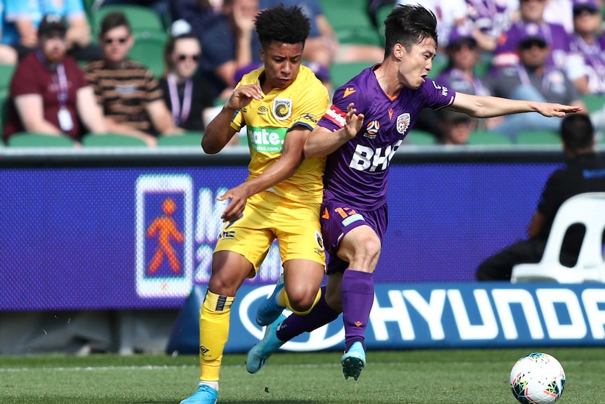 A Central Coast Mariners A-League player and his Perth Glory opponent make contact as they compete for the ball.
