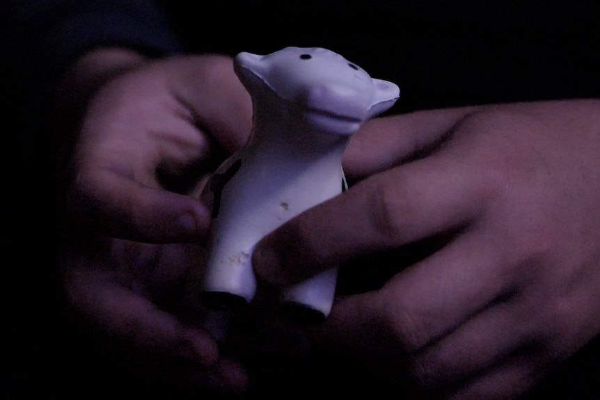 Hands holding a toy dairy cow.