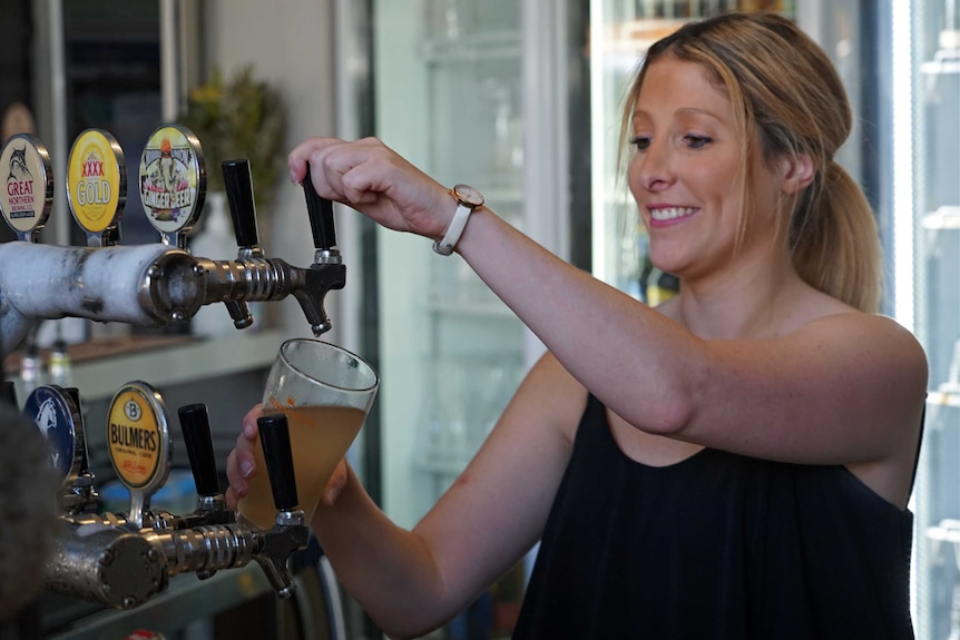 Bartender pours beer at Cavenagh Hotel in Darwin.