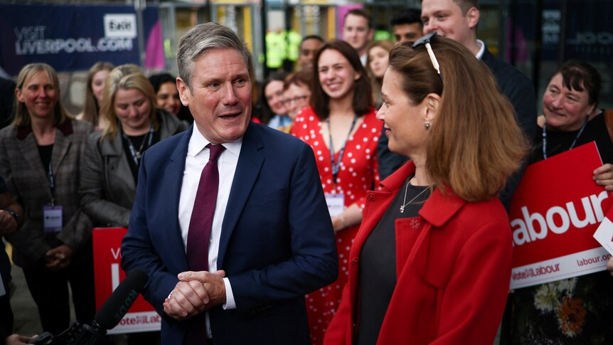 A man in a suit talks to a group of people.