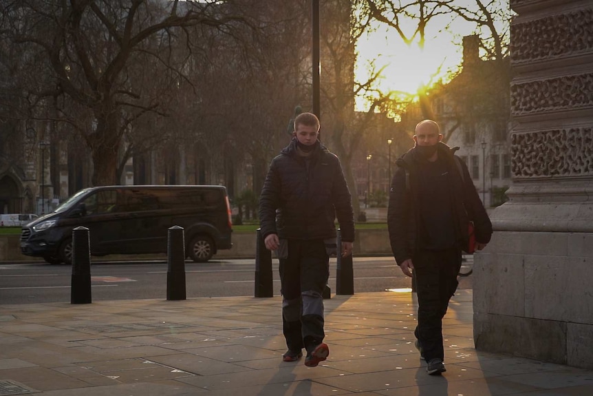 Two workers walk on a sidewalk at Parliament Square in Westminster.
