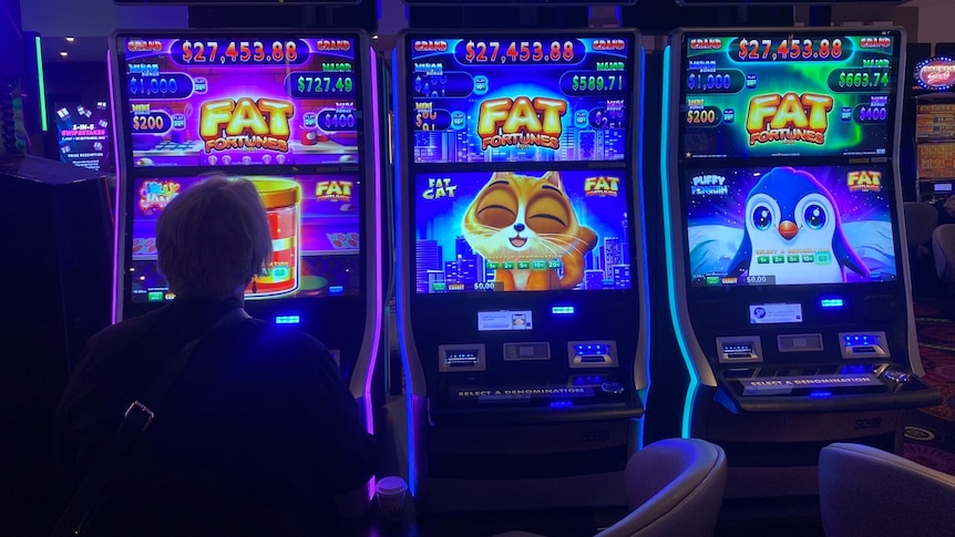 The silhouette of a woman sitting at a colourful pokies machine