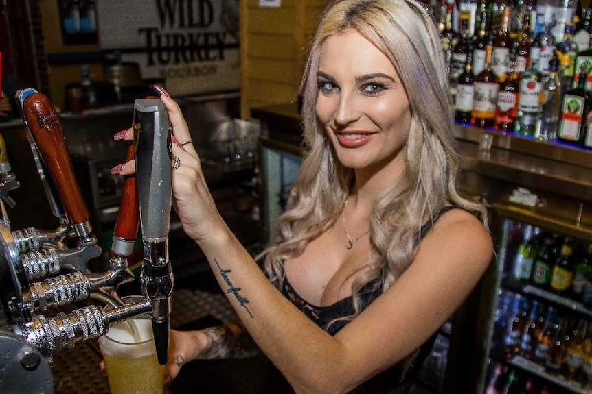 Skimpy barmaid pours a beer.