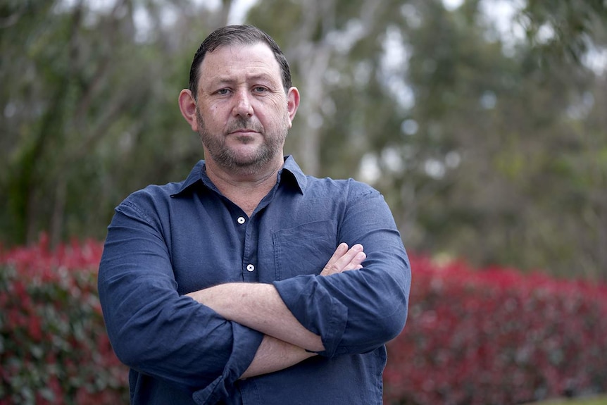 a middle-aged man in front of a tree.