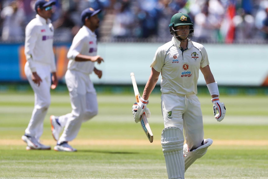Steve Smith carries the blade of his bat in his hand as he walks off after being dismissed