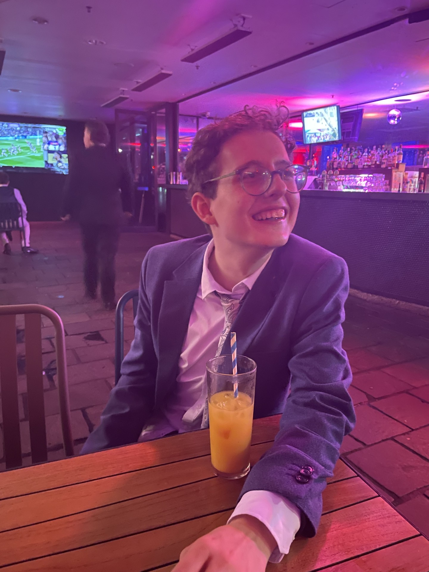 A young man with glasses sitting in a restaurant.