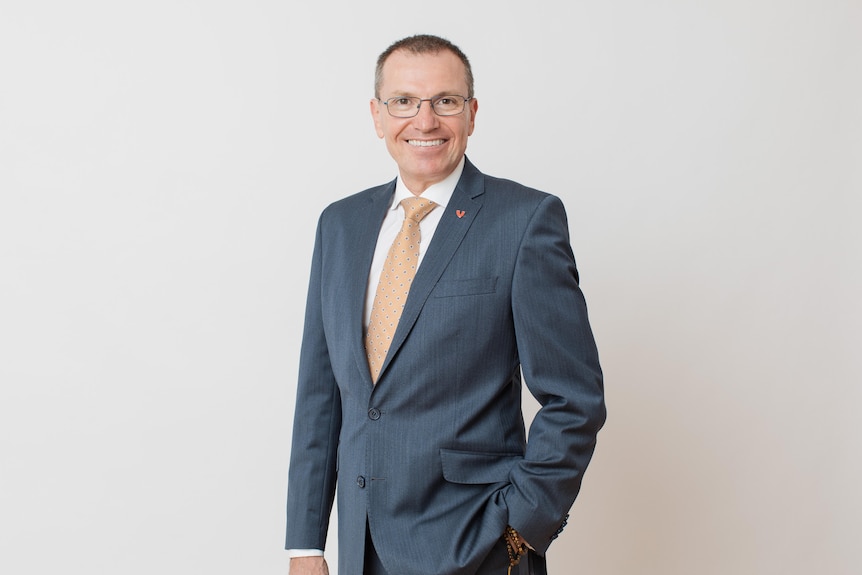 A man in a suit smiles at the camera.