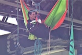 Protester sitting in a hammock under a bridge with a duffle bag