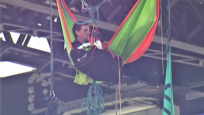 Protester sitting in a hammock under a bridge with a duffle bag