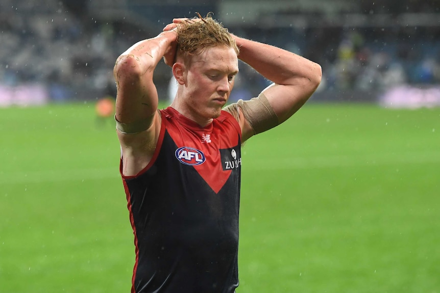 Clayton Oliver with his hands on his heads looking at the ground.