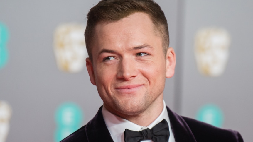 Taron Egerton looks to his right at a red carpet event