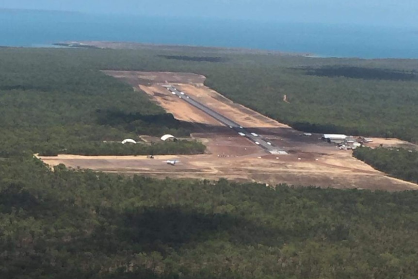Aerial view of an airbase with a runway surrounded by trees.