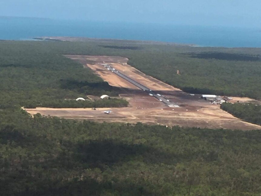 Aerial view of an airbase with a runway surrounded by trees.