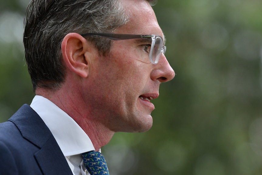 Side shot of the face of a man wearing a collar and tie and glasses. 