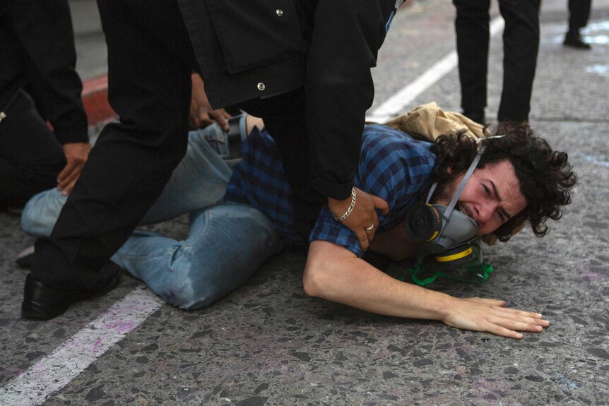 A man is held on the ground while being detained by police near the Guatemalan Congress building