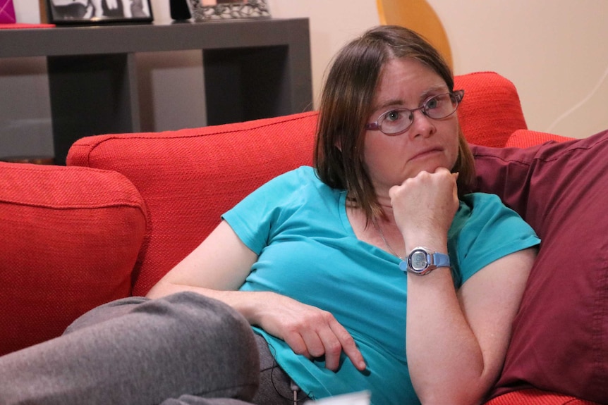 Julia Hales relaxing on a red couch, hand under chin.
