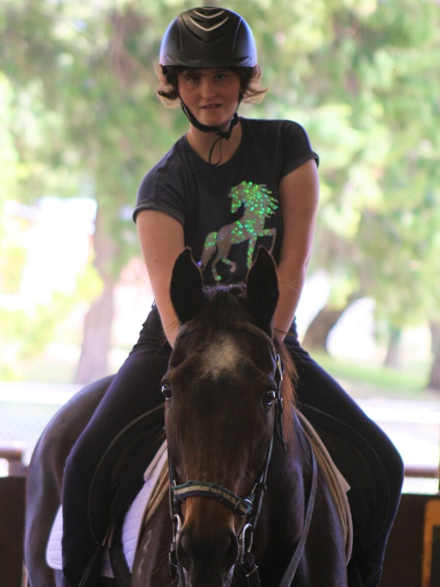 A woman wearing a helmet astride a horse.