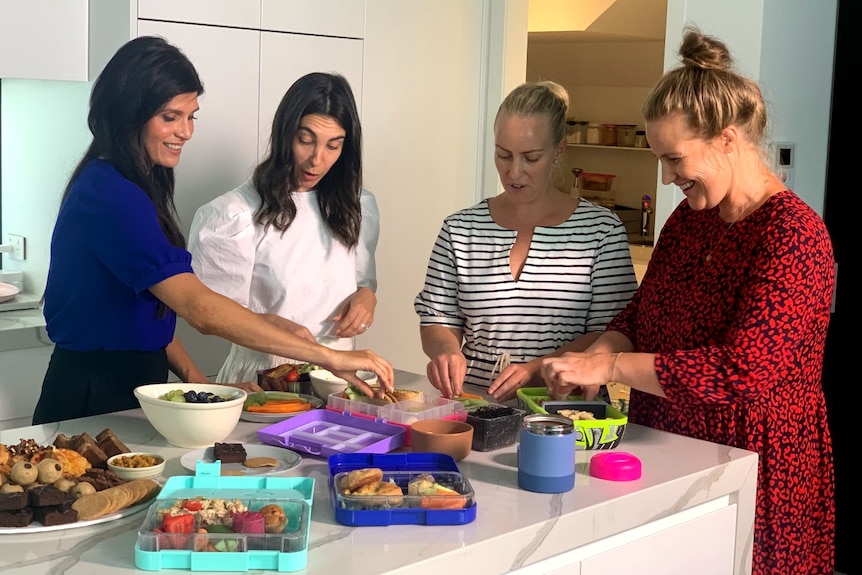 Nutritionist Mandy Sacher (left) shows a group of mums in a kitchen an array of healthy school lunch choices.