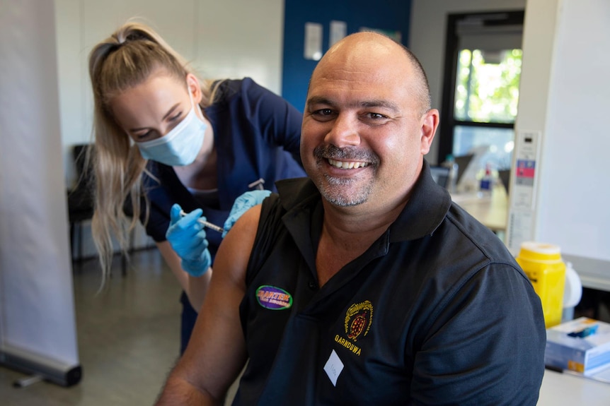 An Aboriginal man smiles for the camera as he receives his COVID-19 vaccination