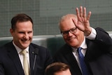 Morrison and Hawke smile as Morrison waves to the camera from the house of representatives backbenches
