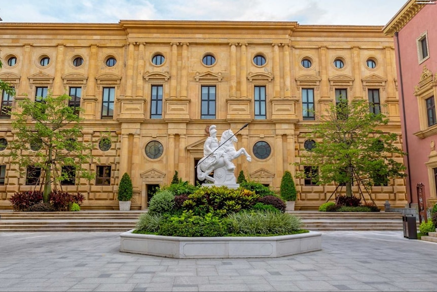 A classical european building with a statue of a man riding a horse.