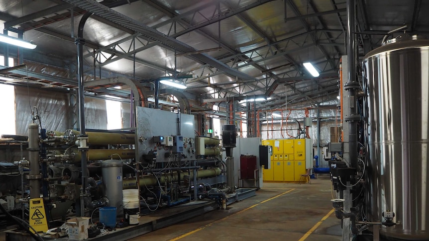 Large silver tanks sit alongside thinner grey tanks in a large shed