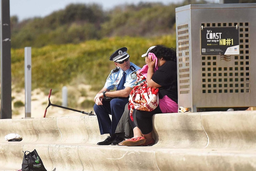 A policeman talks to two people.