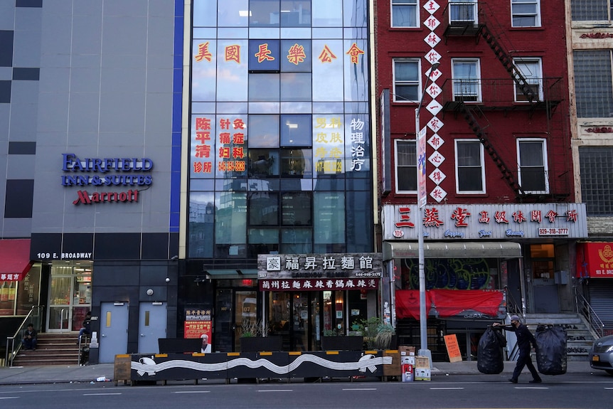 A cluster of high-rise buildings in New York with Chinese text on the shopfront windows. 