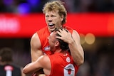 Two Sydney Swans AFL players embrace as they celebrate defeating Collingwood.