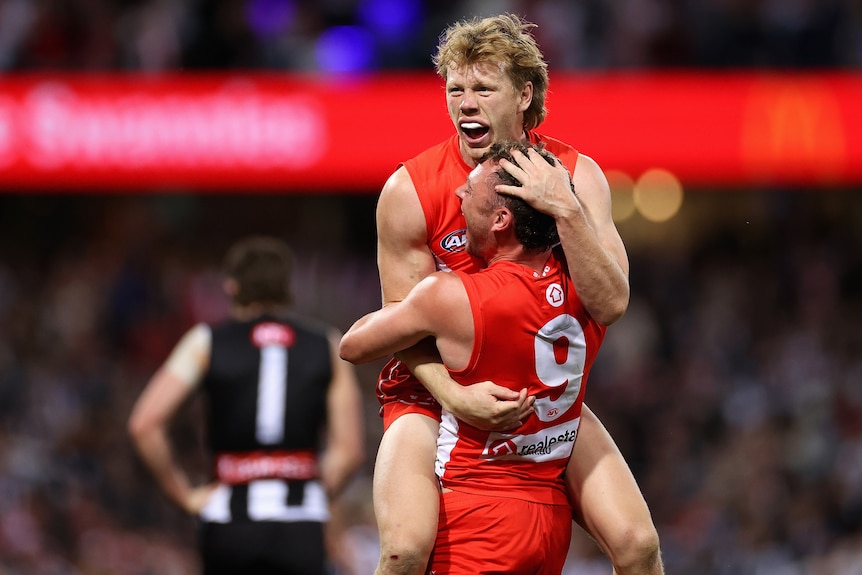 Two Sydney Swans AFL players embrace as they celebrate defeating Collingwood.