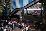 Commuters stand under a pedestrian bridge where the stampede took place.