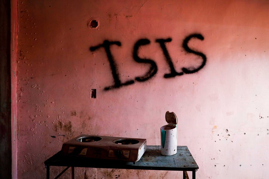A pink wall with 'ISIS' scrawled across it in black graffiti