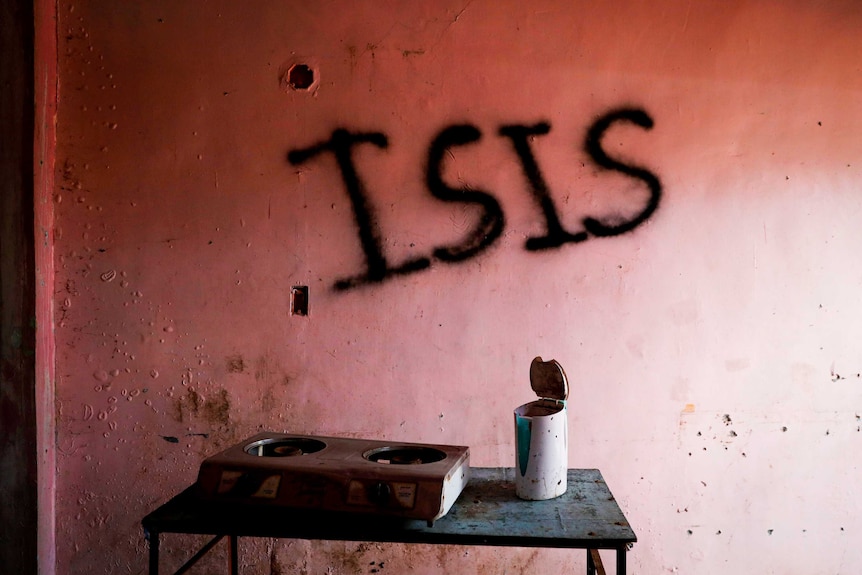 A pink wall with 'ISIS' scrawled across it in black graffiti