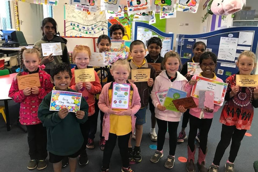 Children in classroom hold up certificates