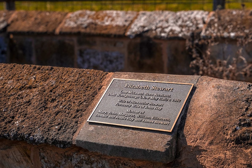 A plaque on an old, fenced-off stone gravesite reads 'Elizabeth Stewart, Born Scotland 1852'.