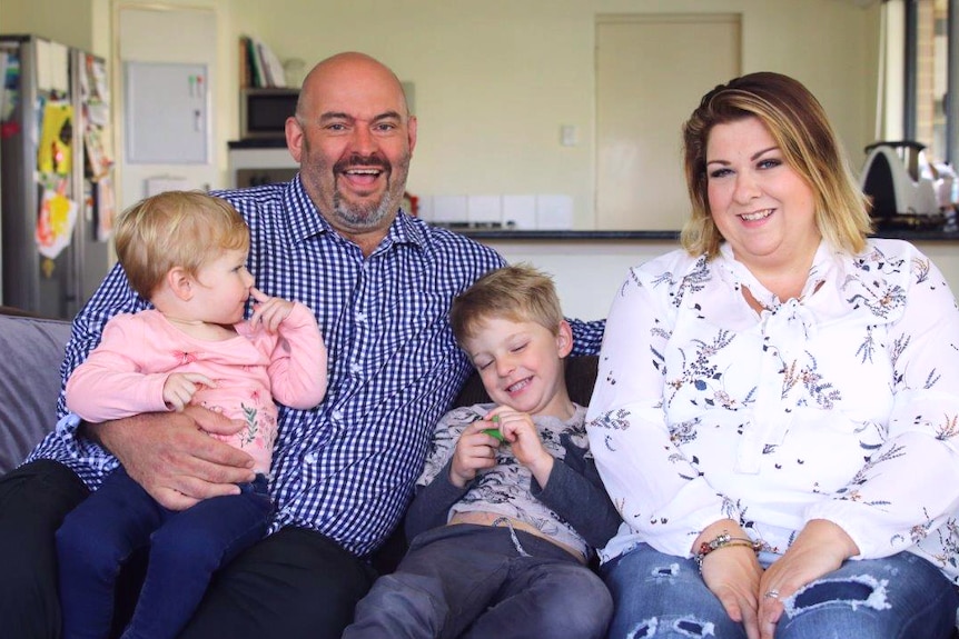 Mark and Verlie laugh on the couch with their children Vivienne and Dexter